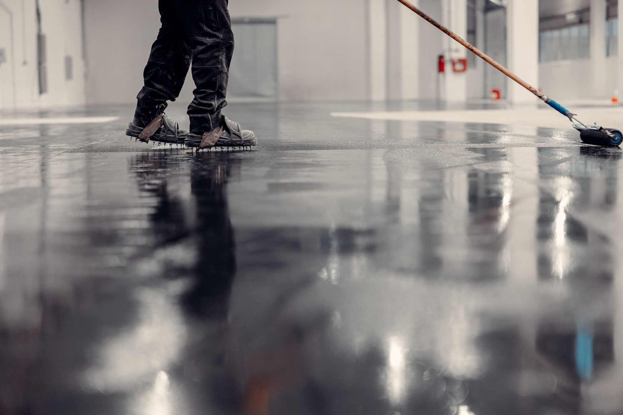 Person cleaning a shiny, wet industrial floor.