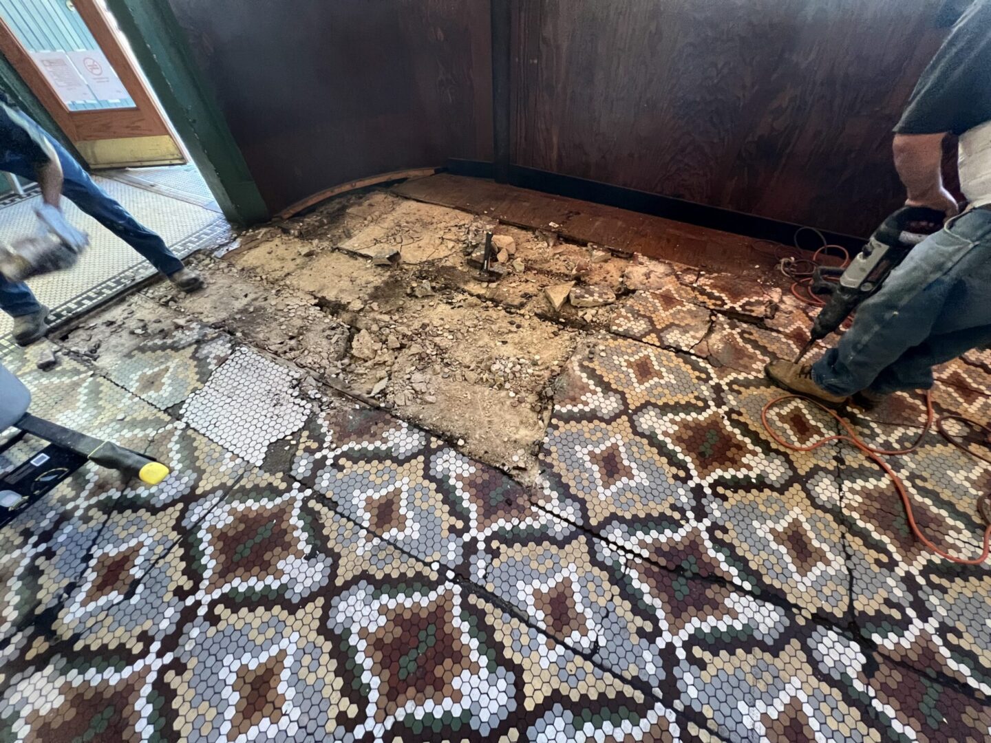 Workers are removing damaged flooring to prepare for new Metallic Epoxy Flooring installation in a construction area.