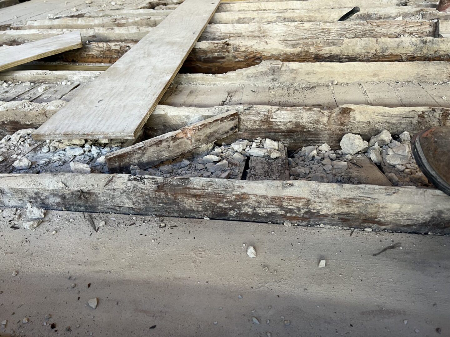 Exposed wooden beams and debris on a construction site, highlighting preparation for Metallic Epoxy Flooring installation.