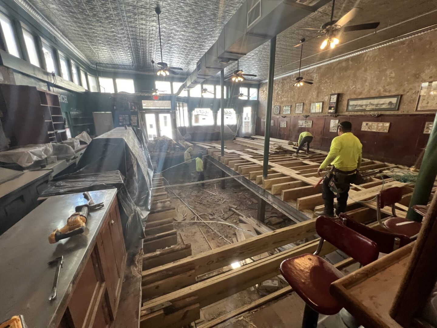 Construction workers are renovating a space with exposed flooring, preparing for new Metallic Epoxy Flooring installation.