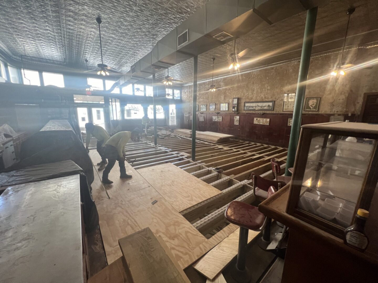 Construction workers install plywood flooring in a renovated space, preparing for Metallic Epoxy Flooring application.