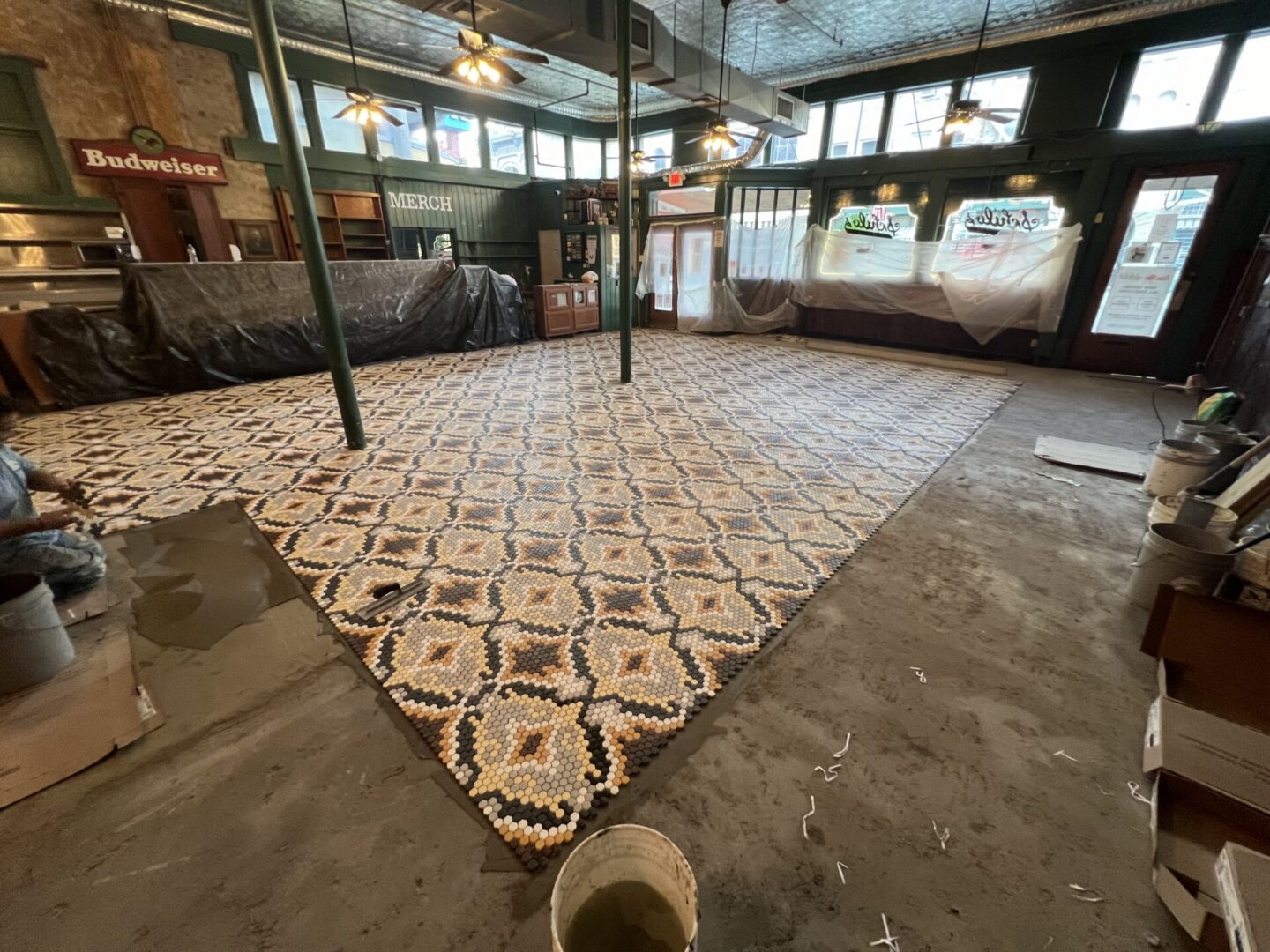 A partially completed metallic epoxy flooring installation showcases a decorative pattern in a commercial space.