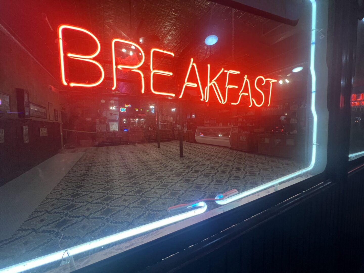 Neon "BREAKFAST" sign illuminates a diner interior featuring patterned flooring, highlighting the potential of Metallic Epoxy Flooring.