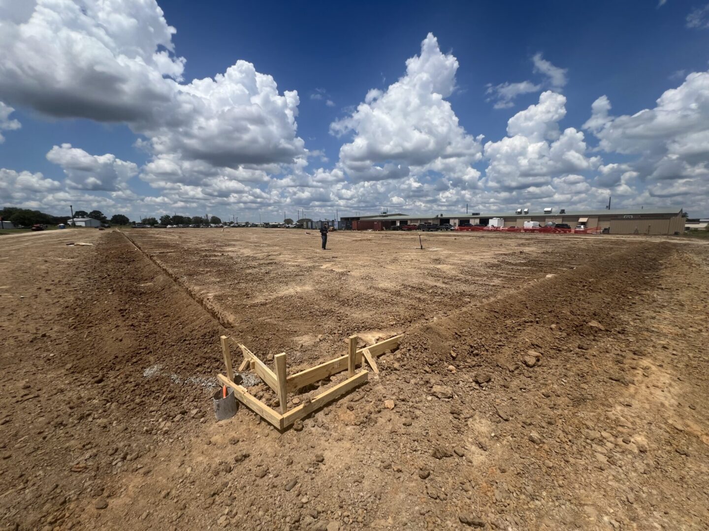 Construction site with a worker surveying land, preparing for projects including Metallic Epoxy Flooring installation.
