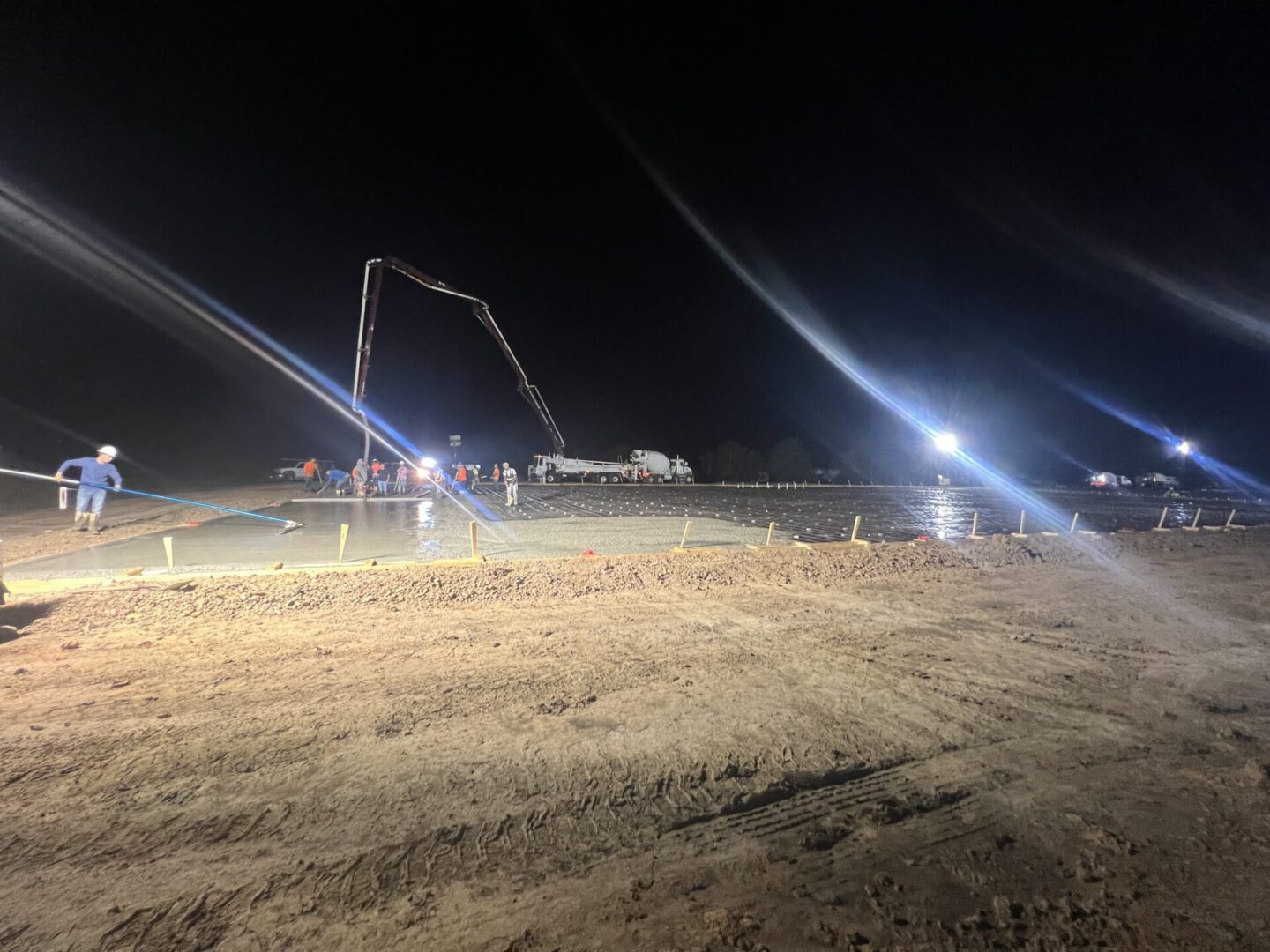 Construction workers pour concrete at night, preparing a surface for Metallic Epoxy Flooring installation.