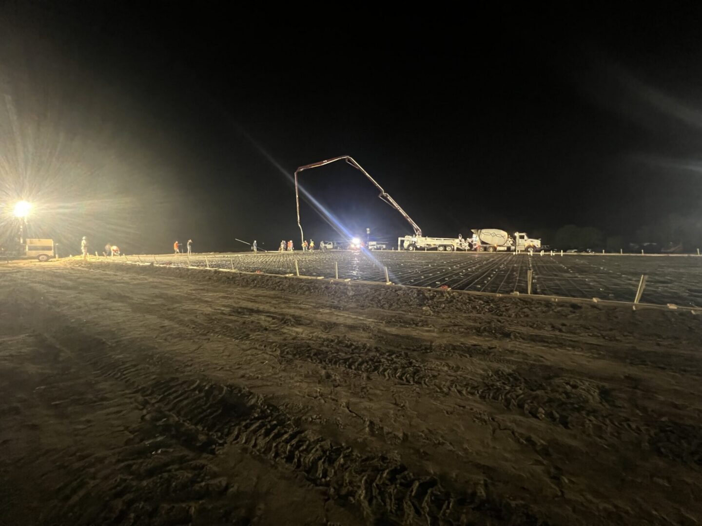 Construction workers pour concrete at night for a foundation, highlighting the process before applying Metallic Epoxy Flooring.