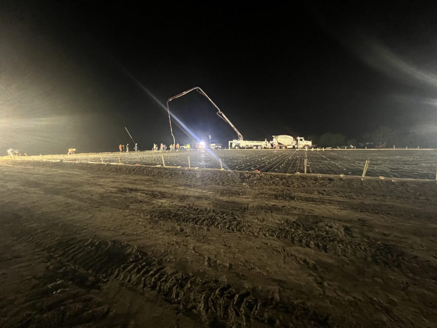 Construction workers operate machinery at night to prepare a site for Metallic Epoxy Flooring installation.