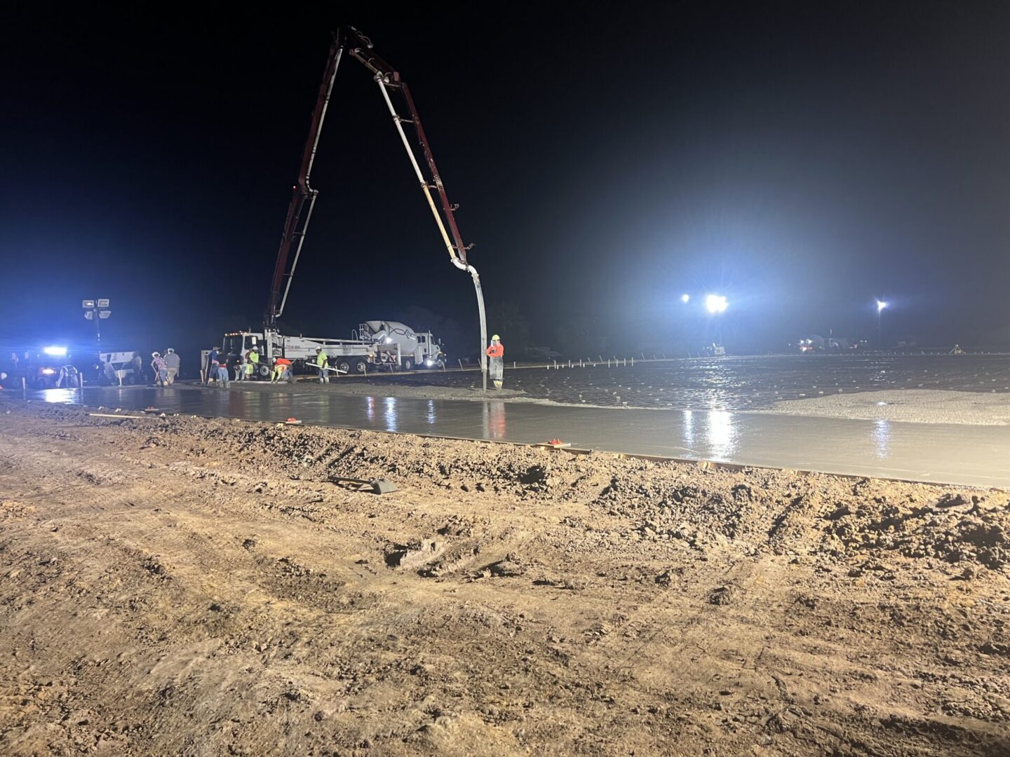 Construction workers pour concrete at night, preparing a surface for Metallic Epoxy Flooring installation.