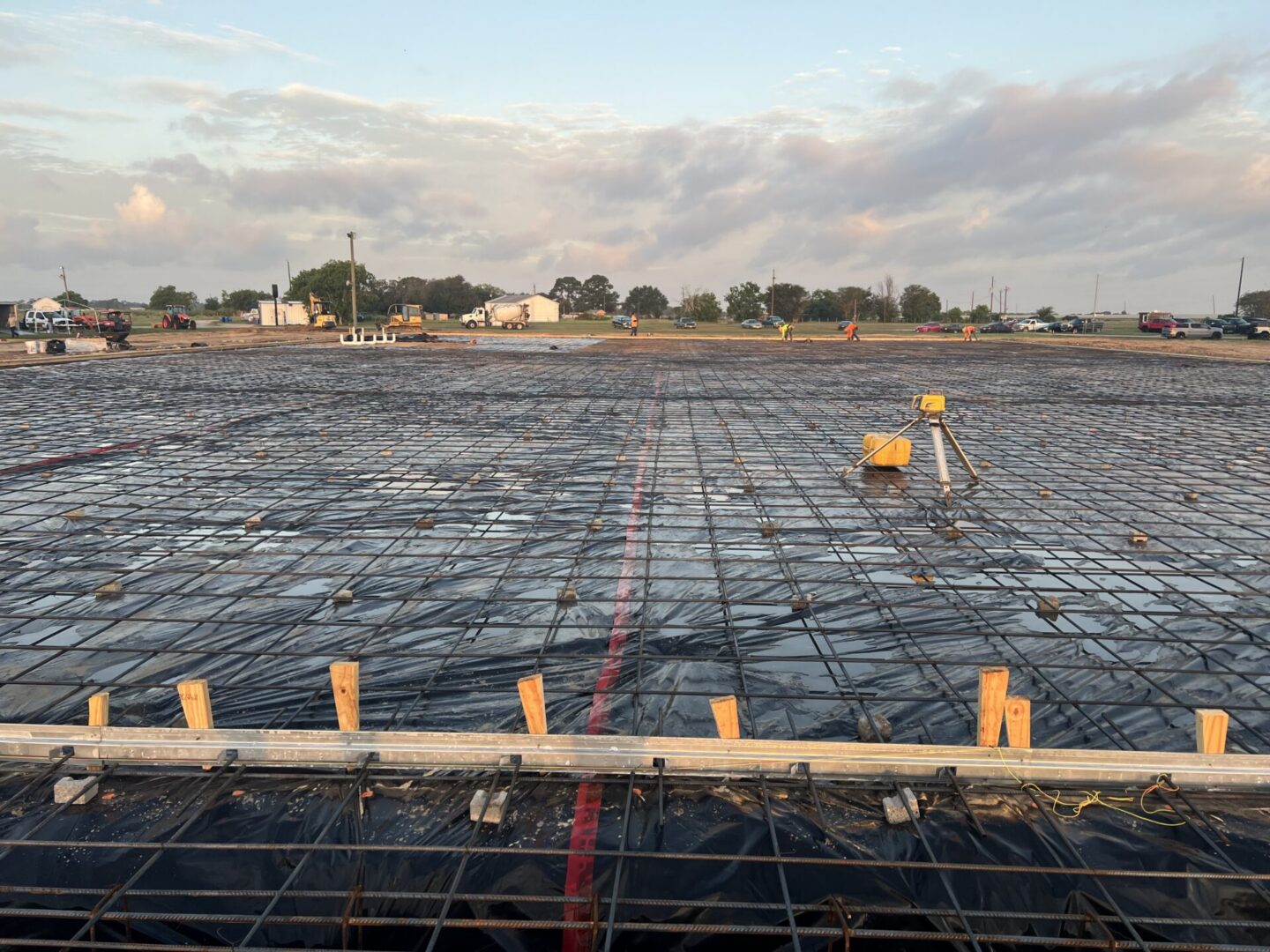 Construction site showing a large area prepared for Metallic Epoxy Flooring with rebar and protective sheeting in place.