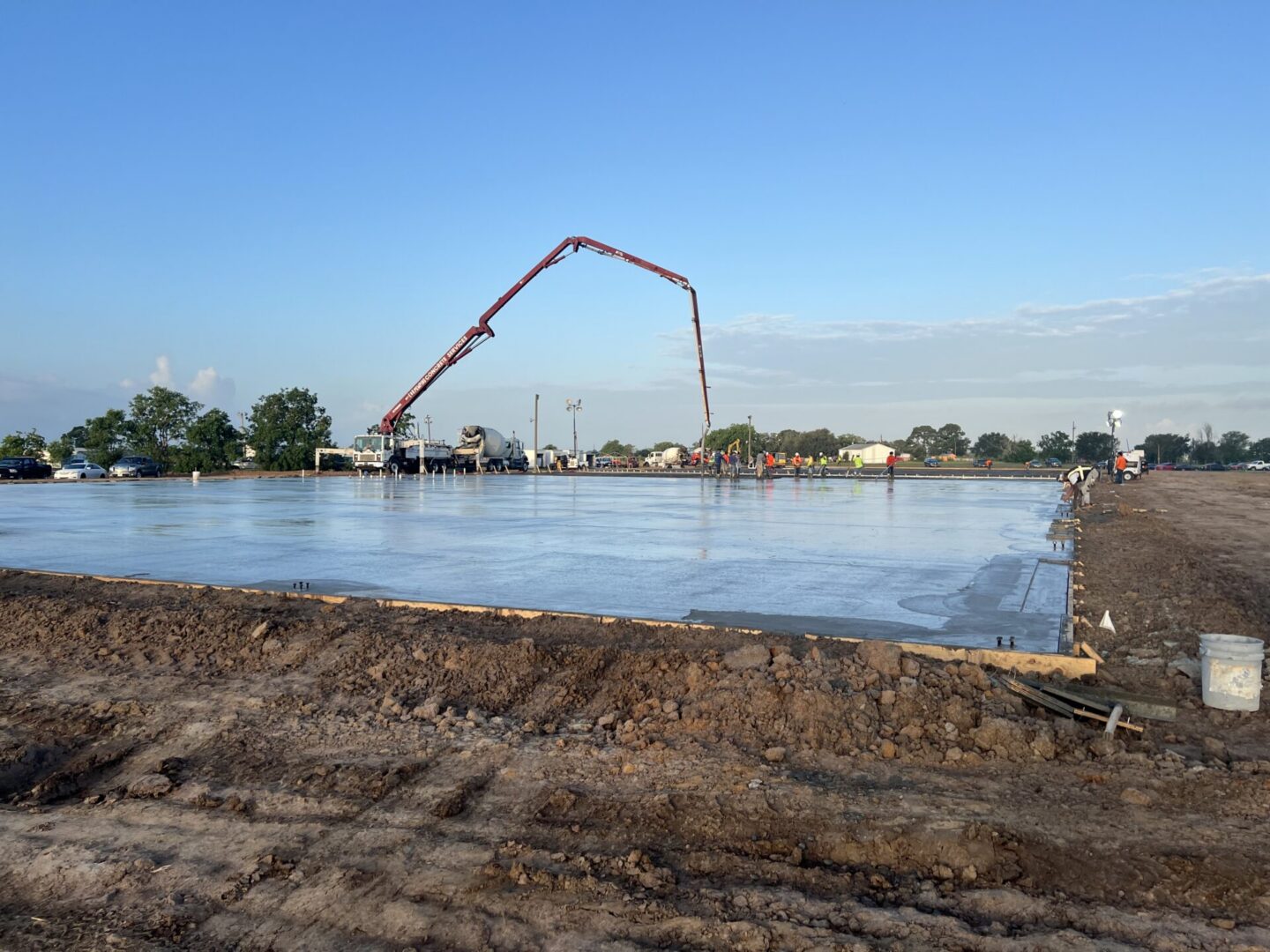 Construction site with workers pouring concrete for a foundation, highlighting the preparation for Metallic Epoxy Flooring.