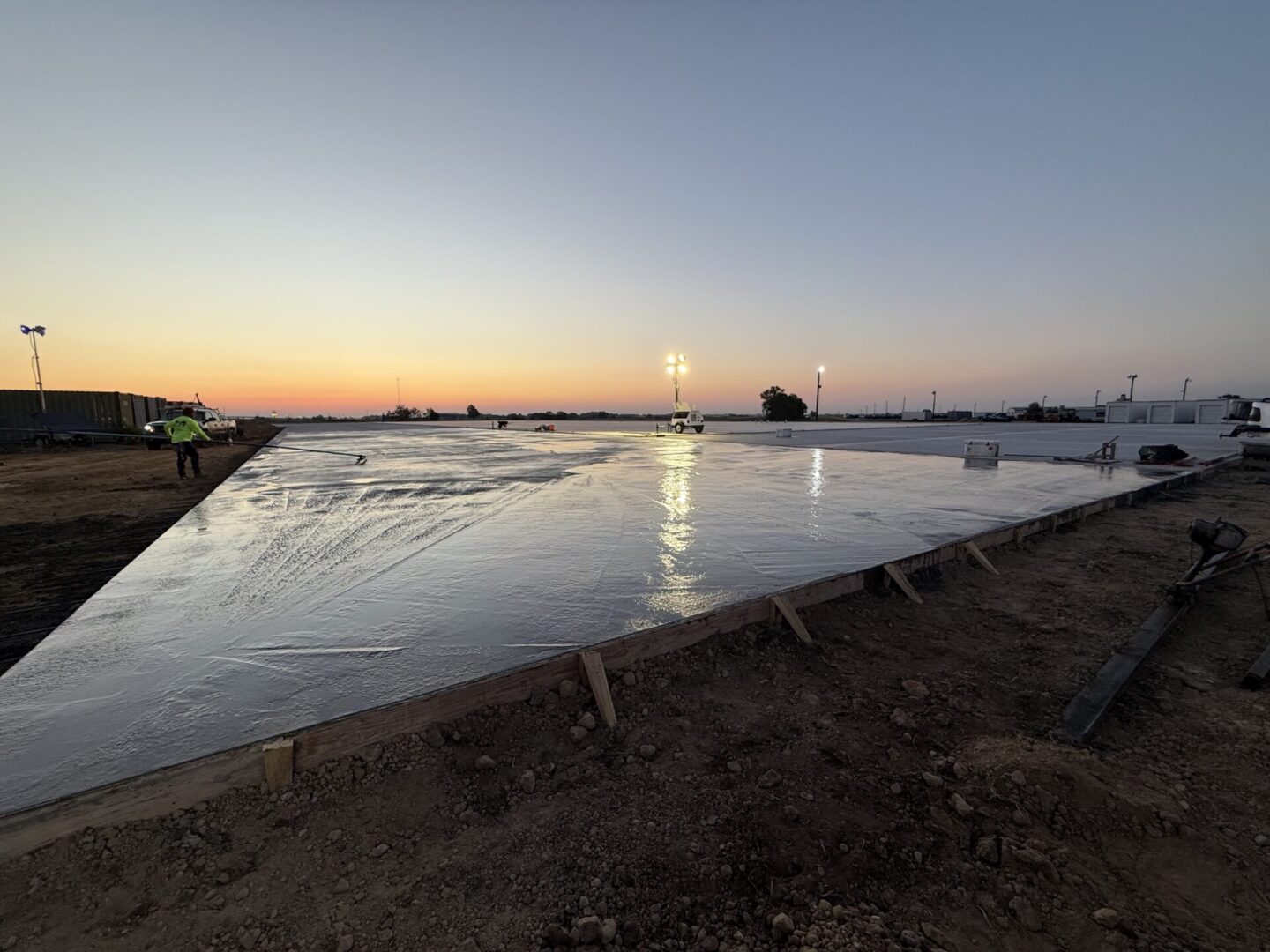 Construction site at sunset showcasing a newly poured metallic epoxy flooring surface.