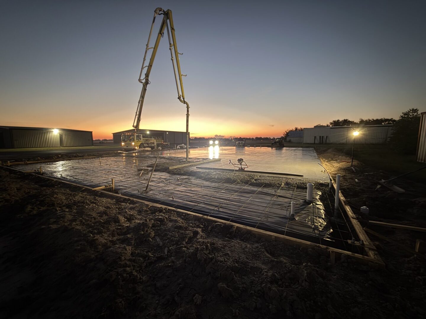 Concrete is being poured at sunset for a construction site, preparing for Metallic Epoxy Flooring installation.