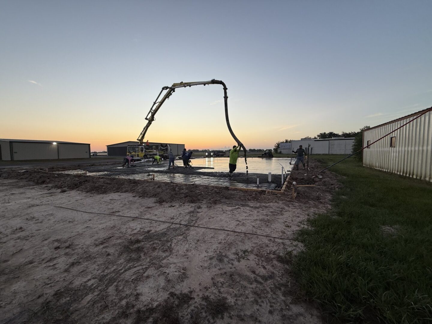 Construction workers pouring concrete at sunset, preparing a foundation for Metallic Epoxy Flooring installation.