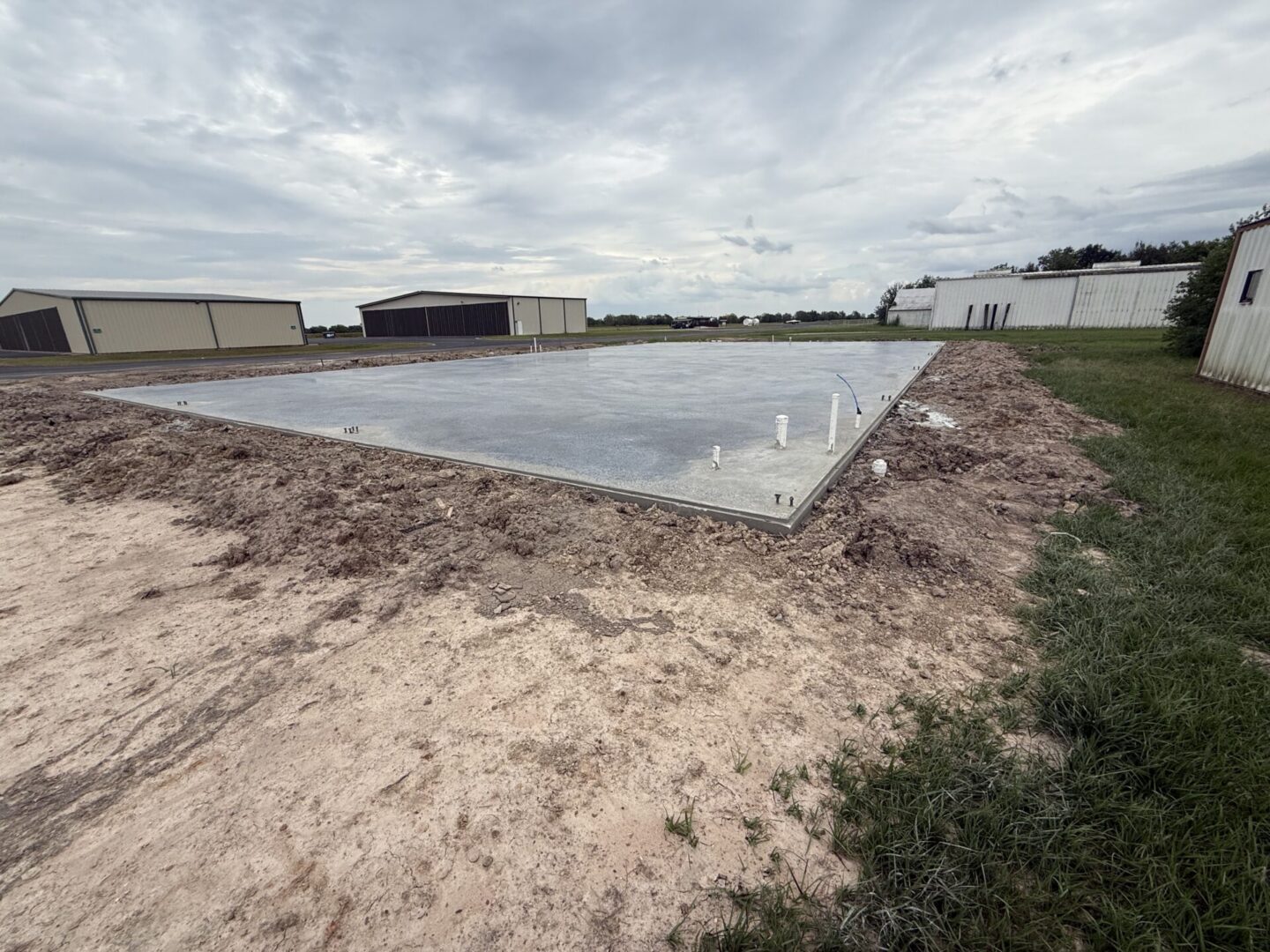 Concrete slab foundation prepared for installation of Metallic Epoxy Flooring, surrounded by construction site elements.