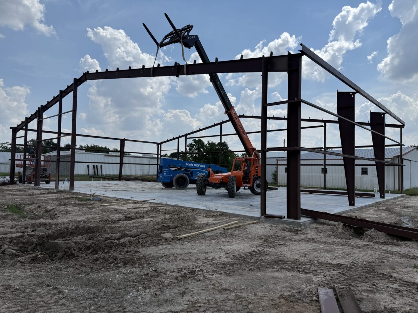Construction site featuring a steel framework with machinery, highlighting the groundwork for Metallic Epoxy Flooring installation.