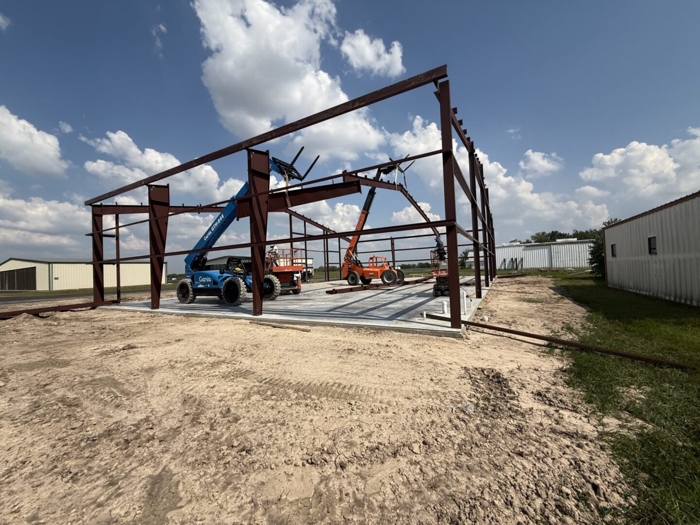 Construction site featuring metal framework and machinery, highlighting the preparation for Metallic Epoxy Flooring installation.