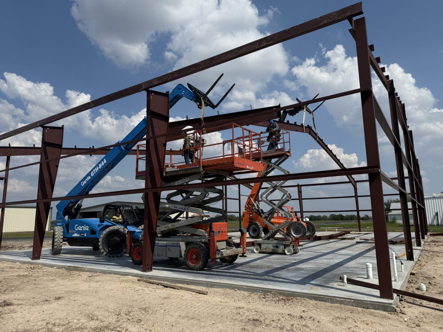 Construction site featuring steel framework and machinery, highlighting the future installation of Metallic Epoxy Flooring.