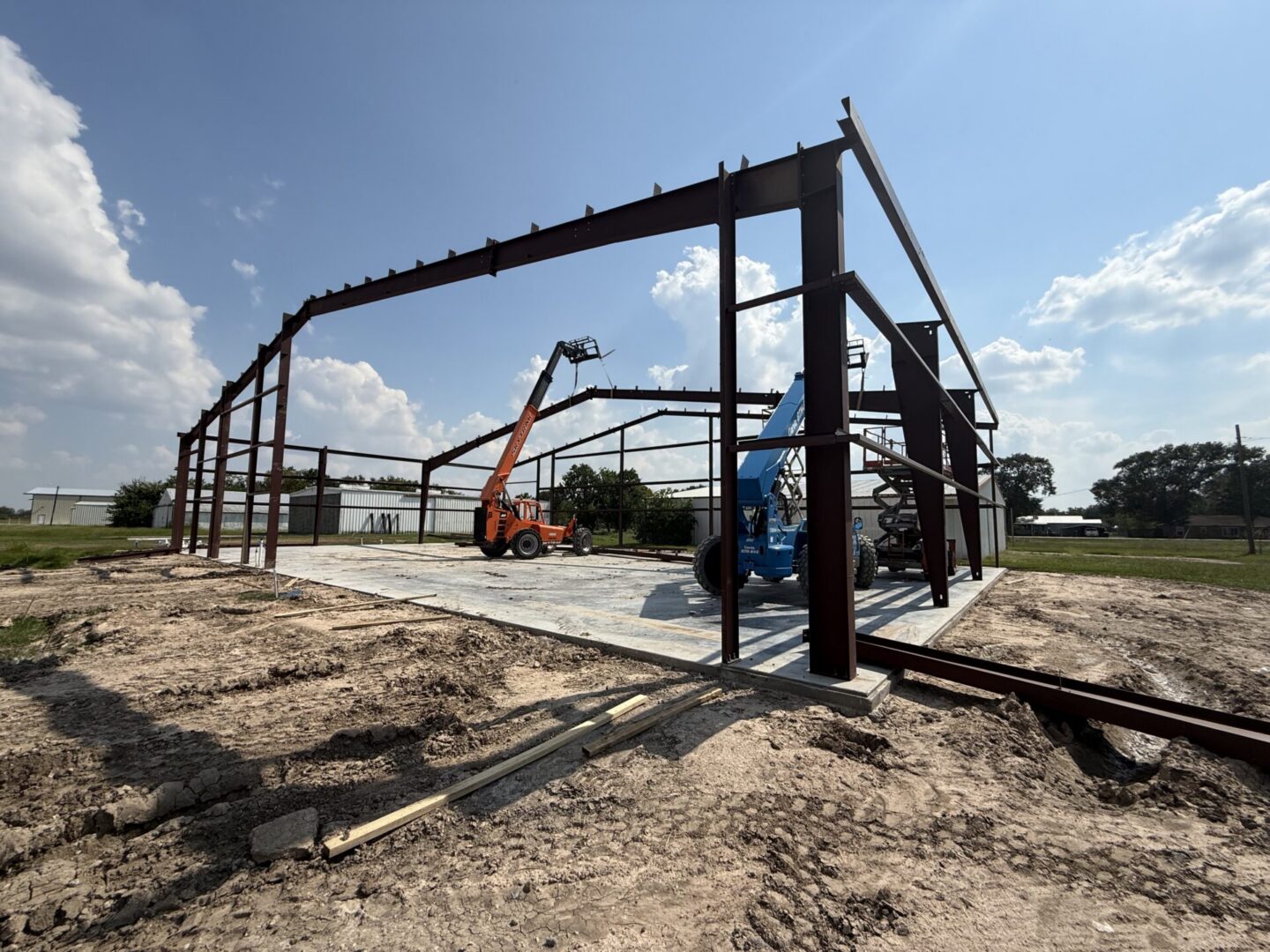 Construction site featuring steel framework and machinery, highlighting the future installation of Metallic Epoxy Flooring.