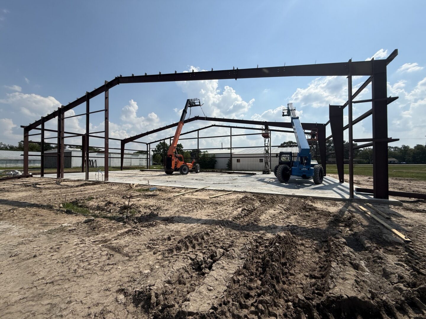 Construction site featuring steel framework and machinery, highlighting the future installation of Metallic Epoxy Flooring.