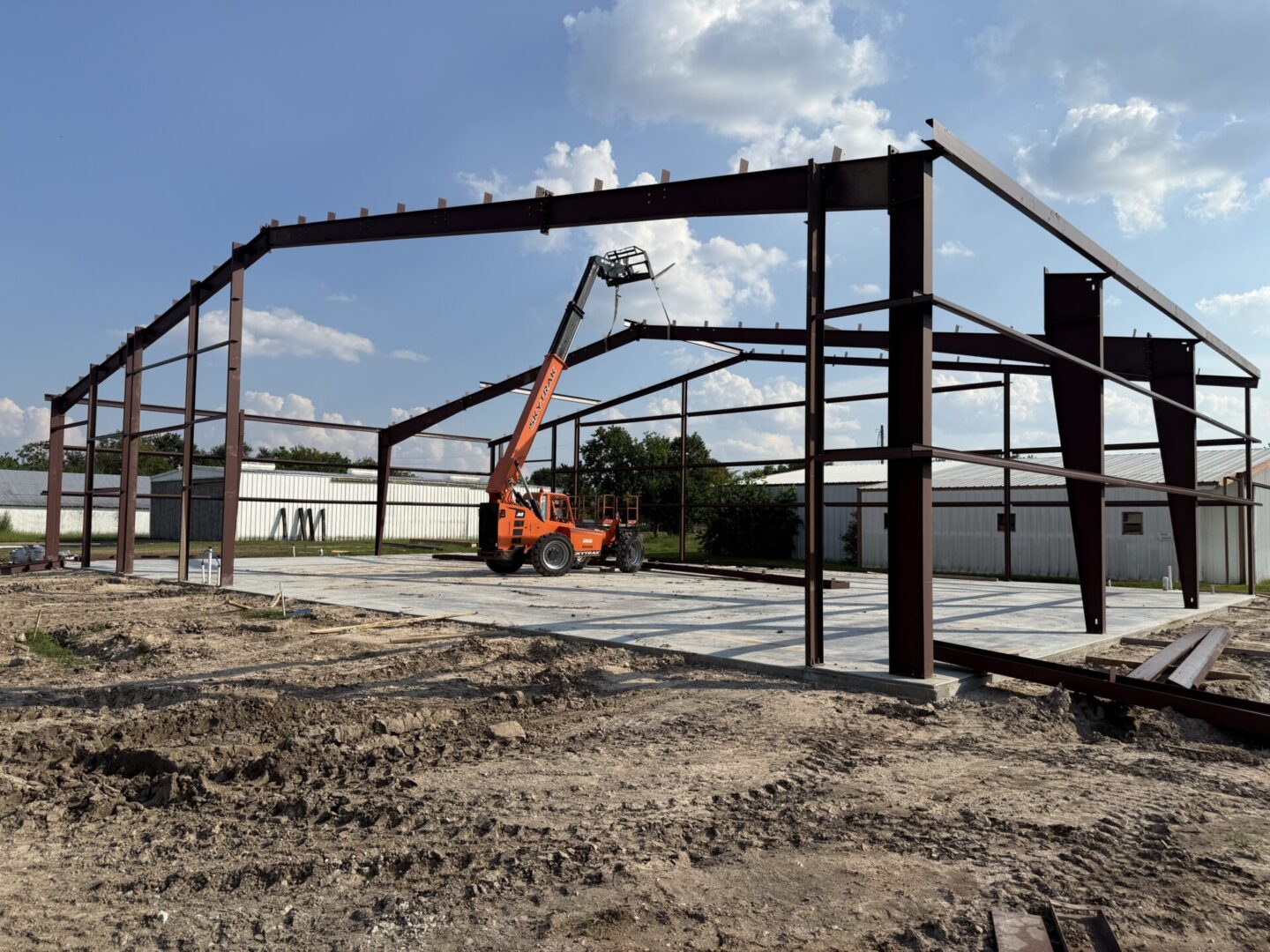 Construction site featuring a steel framework with a lift, preparing for Metallic Epoxy Flooring installation.