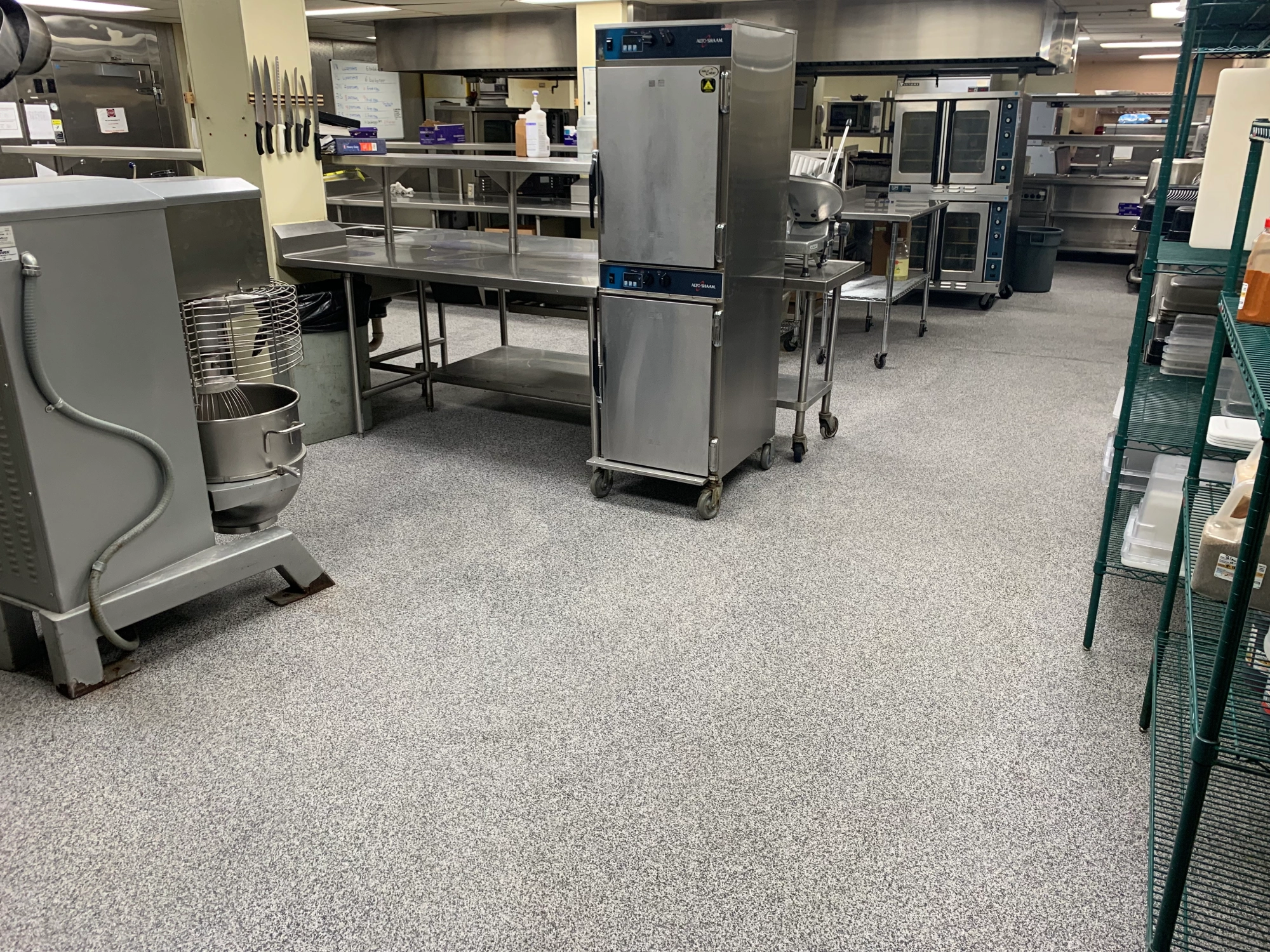 Commercial kitchen with appliances and stainless steel tables.