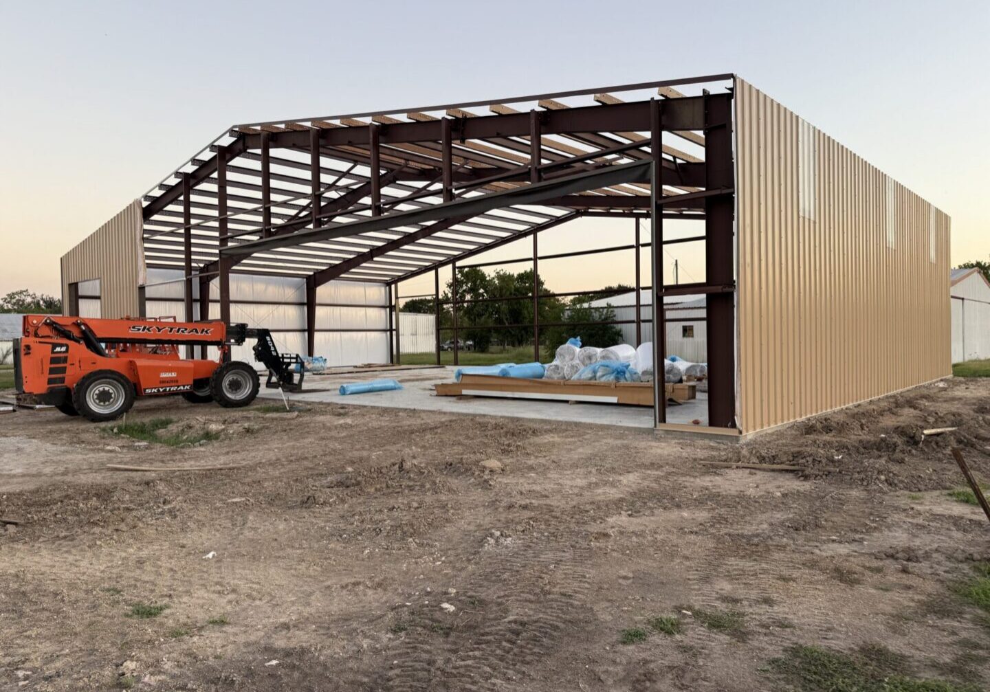 Construction site featuring a partially built metal structure, with materials for Metallic Epoxy Flooring visible inside.