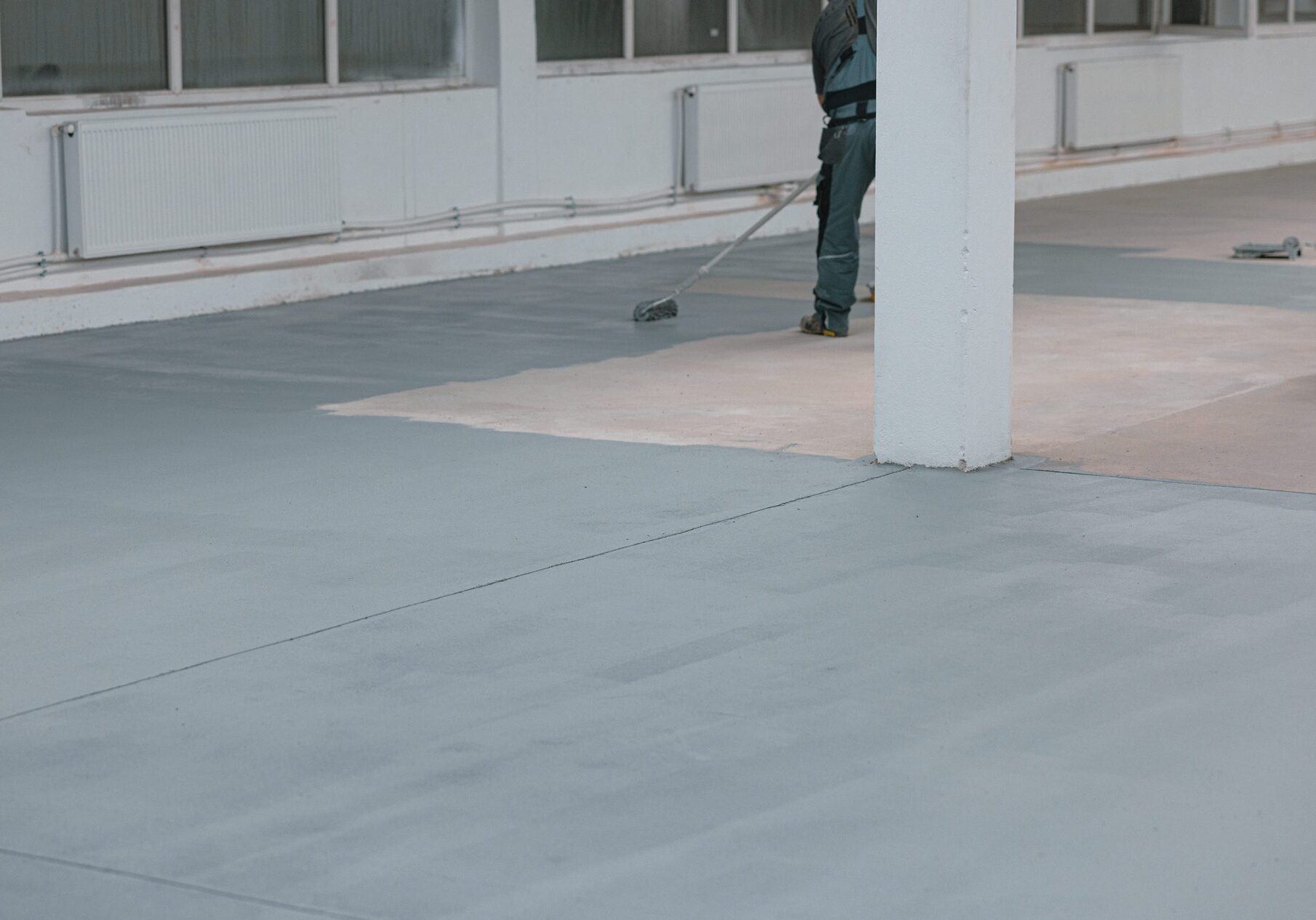 Person painting large indoor concrete floor.