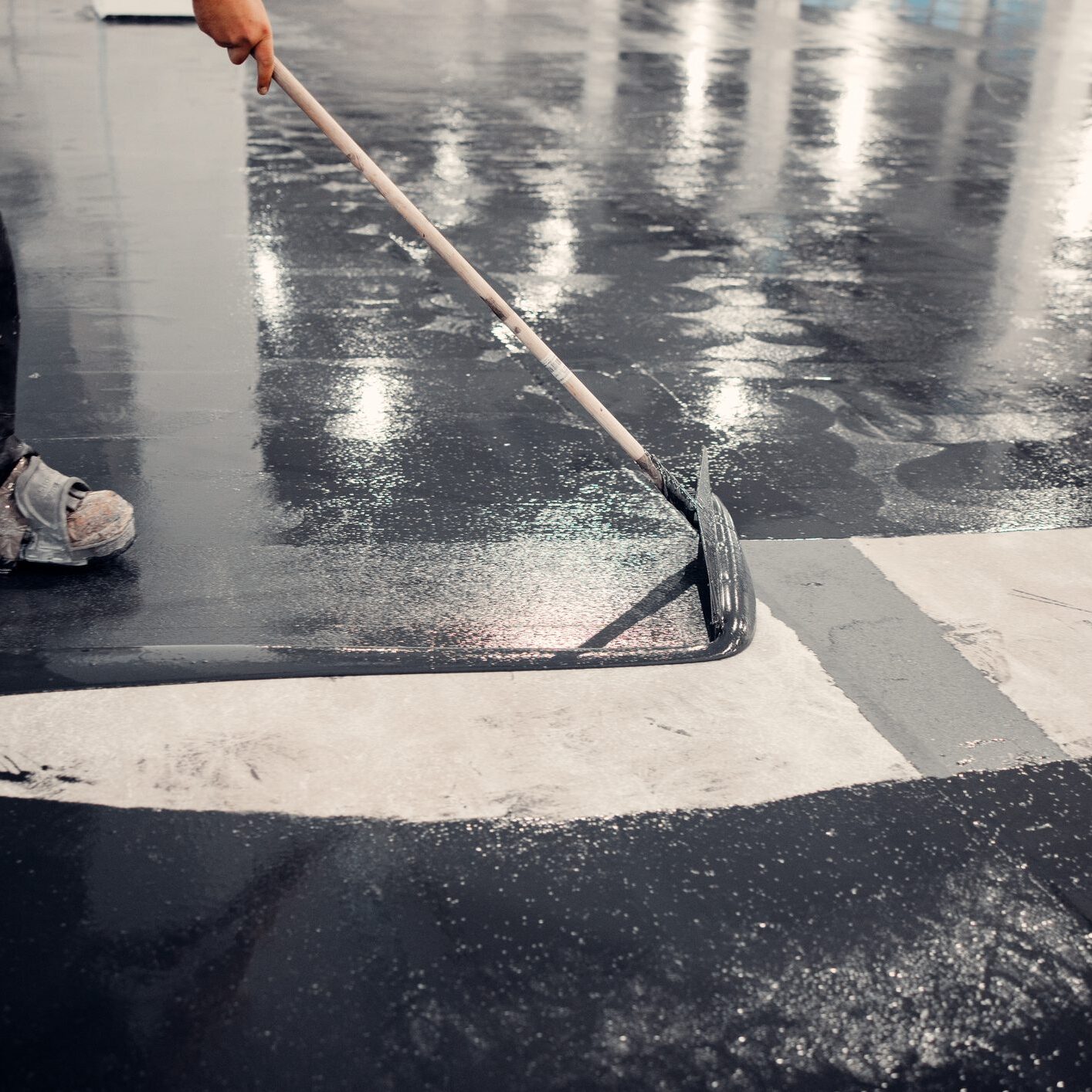 Person applying epoxy on concrete floor.
