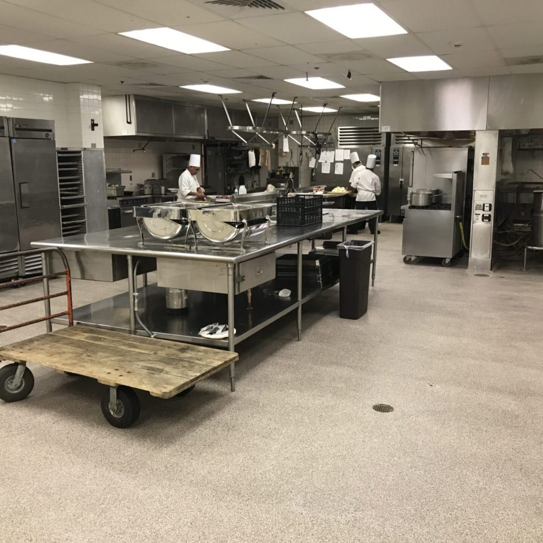 A spacious commercial kitchen showcasing efficient remodel execution with chefs preparing food and organized equipment.